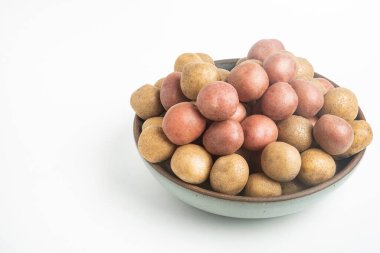 Çiğ ve taze bebek patatesler ustalıkla bir kaseye konulmuş ve beyaz arka plan üzerine kurulmuş..