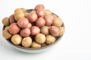 Çiğ ve taze bebek patatesler ustalıkla bir kaseye konulmuş ve beyaz arka plan üzerine kurulmuş..
