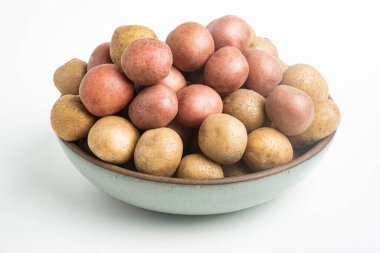Çiğ ve taze bebek patatesler ustalıkla bir kaseye konulmuş ve beyaz arka plan üzerine kurulmuş..