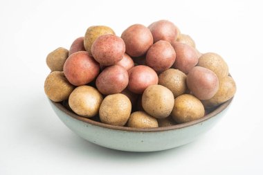 Çiğ ve taze bebek patatesler ustalıkla bir kaseye konulmuş ve beyaz arka plan üzerine kurulmuş..