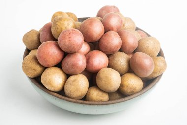 Çiğ ve taze bebek patatesler ustalıkla bir kaseye konulmuş ve beyaz arka plan üzerine kurulmuş..
