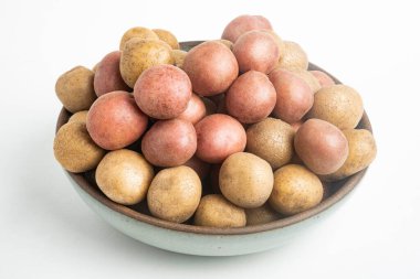 Çiğ ve taze bebek patatesler ustalıkla bir kaseye konulmuş ve beyaz arka plan üzerine kurulmuş..