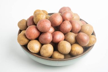 Çiğ ve taze bebek patatesler ustalıkla bir kaseye konulmuş ve beyaz arka plan üzerine kurulmuş..