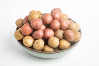 Çiğ ve taze bebek patatesler ustalıkla bir kaseye konulmuş ve beyaz arka plan üzerine kurulmuş..