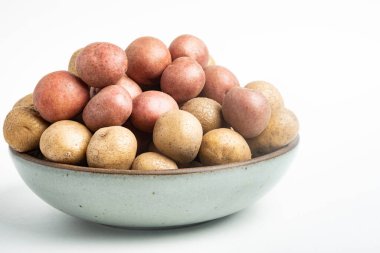Çiğ ve taze bebek patatesler ustalıkla bir kaseye konulmuş ve beyaz arka plan üzerine kurulmuş..