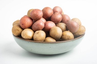 Çiğ ve taze bebek patatesler ustalıkla bir kaseye konulmuş ve beyaz arka plan üzerine kurulmuş..