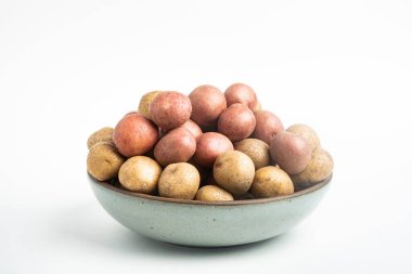 Çiğ ve taze bebek patatesler ustalıkla bir kaseye konulmuş ve beyaz arka plan üzerine kurulmuş..