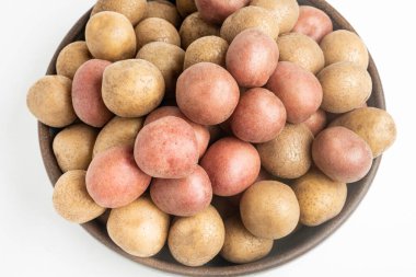 Çiğ ve taze patateslerin üst görüntüsü bir kasede ustalıkla düzenlenmiş ve beyaz arka planda ayarlanmış..