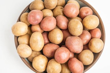 Çiğ ve taze patateslerin üst görüntüsü bir kasede ustalıkla düzenlenmiş ve beyaz arka planda ayarlanmış..