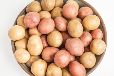 Top view of raw and fresh baby potatoes artfully arranged in a bowl and set on white background. clipart