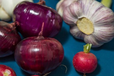 Mavi arka planda sağlıklı sebzeler. Turp. Taze sarımsak (allium, Bulbus Allii Sativ) besin ve eser elementlerin gerçek bir deposudur. Kırmızı tatlı soğan (solaninum) - doğal antioksidan. Sebzeler güzel bir görünüme ve çekici bir colo var