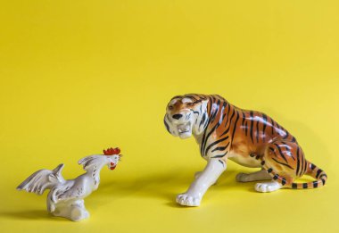 Kaplan ve horoz sarı bir arka plan üzerinde. Porselen heykelcik.