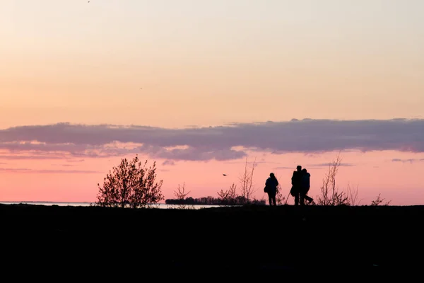 赤い空を背景にした人々のシルエット 海岸の夕日 人々は丘の上を歩いています — ストック写真
