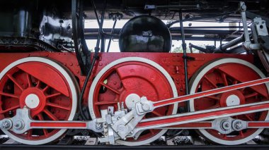 Siyah tren arka plan üzerinde beyaz jantlı kırmızı jantlar. Eski buharlı lokomotif bir müzede park etmiş. Bahar. Gün.