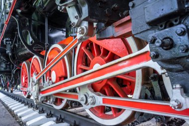 Siyah tren arka plan üzerinde beyaz jantlı kırmızı jantlar. Eski buharlı lokomotif bir müzede park etmiş. Bahar. Gün.