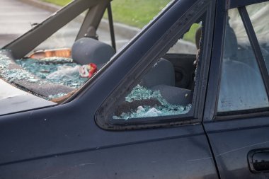Otoparkta binek araba. Hırsızlar camı kırdı ve kulübeden değerli eşyaları çaldı. Bahar. Gün.