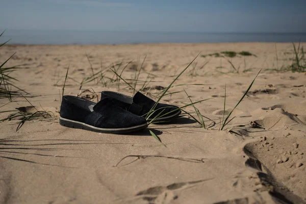 Women's shoes on the sand of the beach. Sandy beach at a resort in Estonia. Narva Bay Narva-Joessuu. Sunny day, summer.