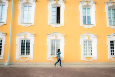 Tarihi bir binanın arka planında insanların bacakları. Turistler bir mimari anıtın önünden geçiyorlar. Yaz güneşli bir gündür..
