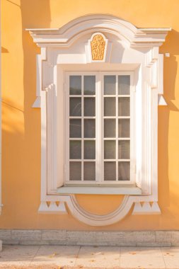 Eski bir binanın penceresi, saray. Çerçeve Barok tarzında sıva yapılır. Duvarların sarı arka plan üzerinde beyaz keten (ocher). Büyük Peterhof Sarayı. Yaz güneşli bir gündür..