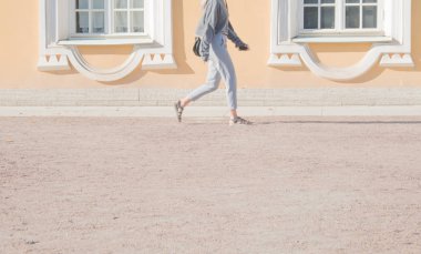 Tarihi bir binanın arka planında insanların bacakları. Turistler bir mimari anıtın önünden geçiyorlar. Yaz güneşli bir gündür..