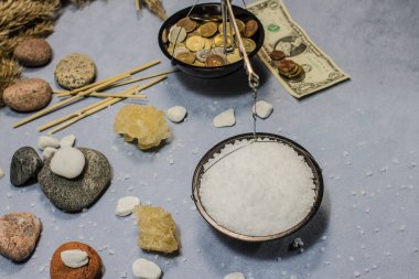 Ağırlıkları, deniz, iyodize tuz ve para ile kolaj. Mavi bir arka plan üzerinde çeşitli baharatlar. Ölçeğin bir tarafında yiyecek, diğer tarafında ise çeşitli sikkeler bulunmaktadır. Çiftçinin, köylünün, çalışkanın ücretlendirmesi.