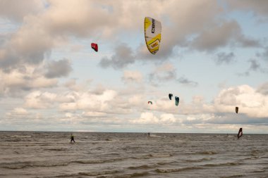 St. Petersburg şehri. Rusya. 3 Ağustos 2019. Gün. Ladoga Gölü'nün kıyısı. Mavi gökyüzü bir arka plan üzerinde çok renkli uçurtma. İnsanlar denizde, bir paraşüt ve rüzgar yardımıyla suda paten sahip dinlenmek. Bulutlarla renkli gökyüzü. Yaz.