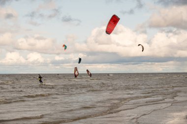 St. Petersburg şehri. Rusya. 3 Ağustos 2019. Gün. Ladoga Gölü'nün kıyısı. Mavi gökyüzü bir arka plan üzerinde çok renkli uçurtma. İnsanlar denizde, bir paraşüt ve rüzgar yardımıyla suda paten sahip dinlenmek. Bulutlarla renkli gökyüzü. Yaz.