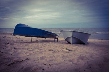 Bulutlu bir günde deniz manzarası. Kıyıda balıkçı tekneleri. Kum plajı. Yaz. Akşam, bulutlu.