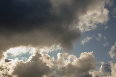Güneş ve bulutlar mavi gökyüzünde. Kümülüs ile bulutlu hava, kara bulutlar. Sonbahar günü. Güçlü bir rüzgar eser, basınç düşük, yağmur eşiği.