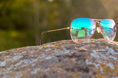 Manzaranın gözlükle yansıması. Renkli, güneş gözlüğü bir granit taş üzerinde yatıyor. Sonbahar, güneşli bir gün. Deniz kıyısı.