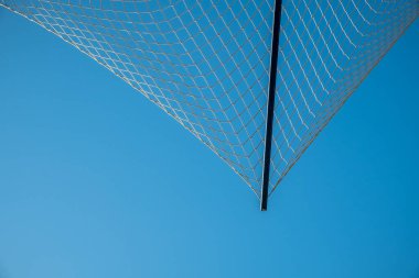 Mavi gökyüzünün arka planında bir ağ. Ağdan yapılmış koruyucu çit. Yüksek binalar.