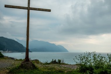 Dağlarla çevrili bir manzara. Tepeler ve deniz manzaralı panoramik bir manzara. Çakıl taşı plajı. Taşlar, sahildeki kayalar, dağlardaki yeşil bitki örtüsü. İyi günler. Çoğunlukla bulutlu. Georgia.