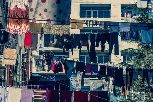 Laundry is hanging on the clothesline. Ropes are pulled between houses in the city. The clothes are air dried. Sunny. Day. Georgia.