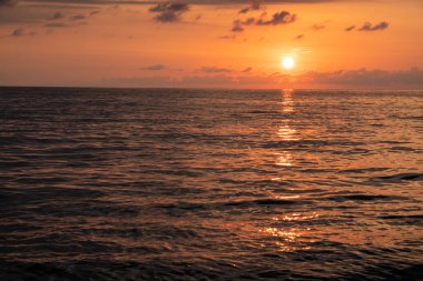 Denizde gün batımı. Kırmızı, sarı gökyüzü. Mavi bulutlar. Güneş suya batıyor. İyi akşamlar. Karadeniz. Georgia.