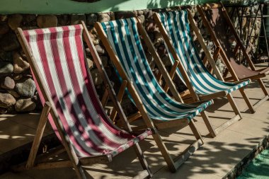 Misafir evinin avlusunda boş çizgili güneş şezlongları. Kumaş, turistler için katlanır sandalyeler. İyi günler. Yaz. Georgia mı? Tatil.