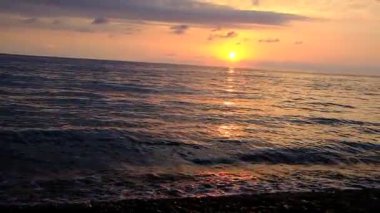 Denizde gün batımı. Kırmızı, sarı gökyüzü. Mavi bulutlar. Güneş suya batıyor. İyi akşamlar. Karadeniz. Georgia.