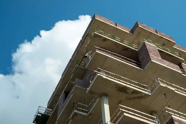 Frame of a monolithic house. Reinforced concrete structures of floors and columns. Incomplete construction of a high-rise building. Apartments under construction against the blue sky. Summer. Day. Georgia.