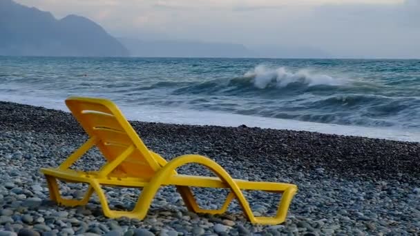 海滨的黄色塑料日光浴床 卵石滩是空的 海上的一场小风暴 不是游客 晚上好主要是多云 格鲁吉亚 — 图库视频影像