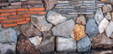 Taş ve tuğla mozaiği. Duvar doğal kaya ve çakıl taşlarından yapılmıştır. Doğal malzemelerin dokusu. Renkli bir geçmiş. Gün güneşli. Georgia.