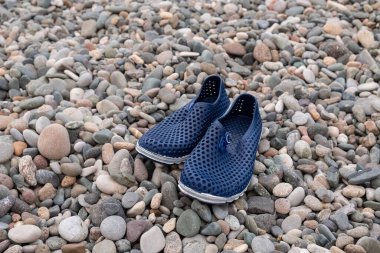 Mavi lastik banyo terlikleri. Deniz kenarında çakıl taşlı plaj ayakkabıları..