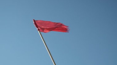 Deniz kenarındaki kurtarma kulesi. Suyun yanındaki kırmızı gözlem noktası. İşaret, kırmızı bayrak. Rüzgar kırmızı bayrağı dalgalandırıyor. Sancak rüzgardan titriyor. Georgia mı? İyi günler, güneşli. Yaz.