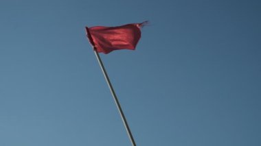 Deniz kenarındaki kurtarma kulesi. Suyun yanındaki kırmızı gözlem noktası. İşaret, kırmızı bayrak. Rüzgar kırmızı bayrağı dalgalandırıyor. Sancak rüzgardan titriyor. Georgia mı? İyi günler, güneşli. Yaz.