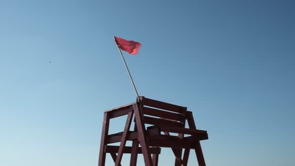 海のそばの救助塔 水の近くに赤い展望台 風が赤い旗をなびかせる 旗は風になびく ジョージア — ストック動画