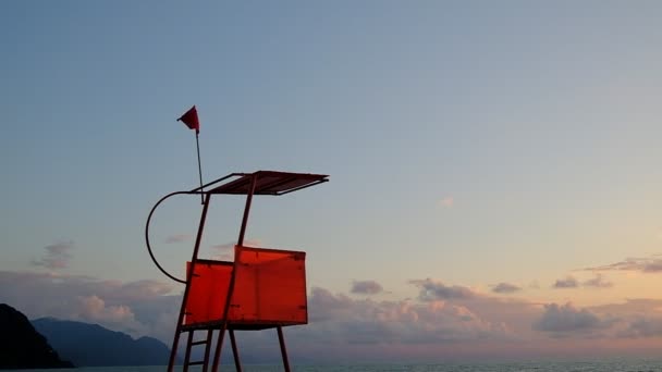 海のそばの救助塔 水の近くに赤い展望台 風が赤い旗をなびかせる 旗は風になびく ジョージア — ストック動画