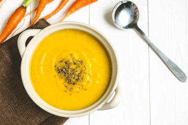 Beyaz masada havuç ve bir kaşık ile kabak çorbası.