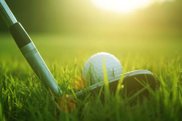 Club de golf borrosa y pelota de golf de cerca en el campo de hierba con sol —  Fotos de Stock