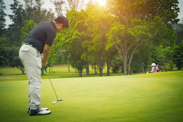 गोल्फर सुंदर गोल्फ कोर्समध्ये गोल्फला छिद्रात टाकतो. द. — स्टॉक फोटो, इमेज