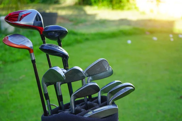 Closeup old golf bags on the green. Set of golf clubs over green field background.