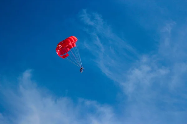 Havada mavi gökyüzüne karşı kırmızı parasailing hızlı — Stok fotoğraf