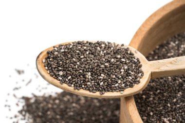 Tahta kaşık bazı yayılan konuşabilerek yukarıda da görüleceği bulanık beyaz arka plan üzerinde ahşap bir kaseyle üstüne chia tohum yakın çekim